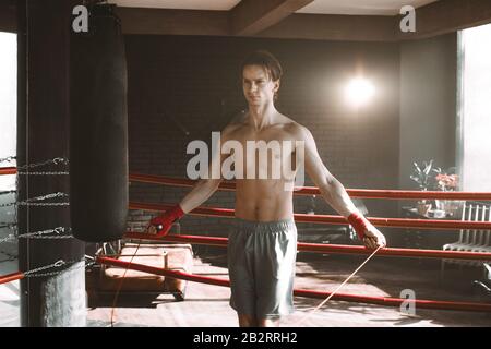 Un jeune sportif s'entraîner avec une corde de saut, se réchauffer sur le ring de boxe dans la salle de gym. Sport, mode de vie sain, concept de boxe Banque D'Images