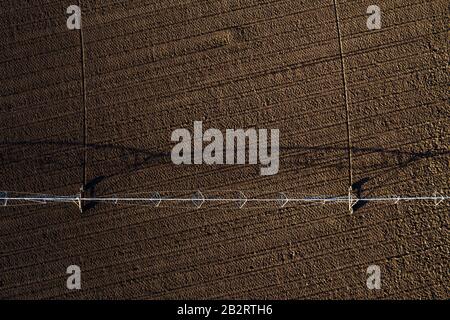 Vue aérienne du système d'irrigation à pivot central sur le champ labouré à partir de drone pov, de l'agriculture et de l'équipement agricole Banque D'Images