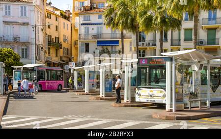 Cannes, FRANCE - AVRIL 2019 : bus dans la gare routière du centre de Cannes. Un petit bus électrique est stationné en arrière-plan. Banque D'Images