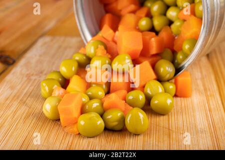 Une CAN ouverte avec un mélange de pois et de carottes. Aliments conservés dans le ménage. Fond clair. Banque D'Images