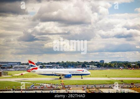 British Airways Airbus A320-232, en hôtel d'affaires, debout sur la piste de l'aéroport Heathrow de Londres, vue du terminal 3 sous des nuages sombres et sombres Banque D'Images