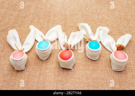 Concept d'oeuf de lapin de Pâques (lapin), décoration de disposition de table. Œufs roses (rosés) et bleus avec serviettes sur fond de lin. Banque D'Images