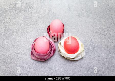 Œufs roses (rosés) de Pâques dans les nids de ruban en satin à pois de polka. Sur fond de pierre en rayons ensoleillés. Banque D'Images