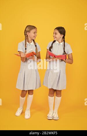 Intérêt sincère. Bibliothèque de l'école. Des livres éducatifs pour l'école. La lecture de livres. La lecture et l'interprétation. Les petits enfants holding books fond jaune. Peu de filles avec des livres pour enfants ou de l'encyclopédie. Banque D'Images