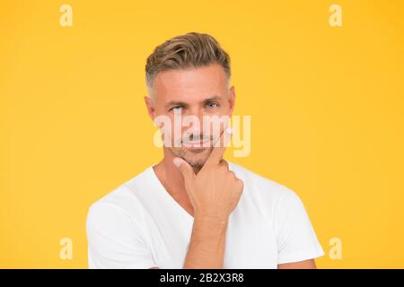Demandez à barber de se raser. Homme sérieux toucher barbe cheveux fond jaune. Beau gars avec visage non rasé. barbier. Services de coiffure. Salon de coiffure. Toilettage masculin. Soins de la peau et des cheveux. Barbershop. Banque D'Images