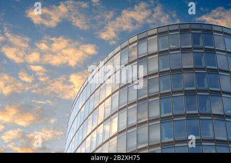Bloc de bureaux ovale à Bruxelles sous un ciel bleu nuageux Banque D'Images
