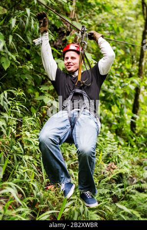 Tourisme Masculin Cultivé Portant Des Vêtements Décontractés Sur Zip Line Ou Canopi Expérience Dans La Jungle Aquatique Équatorienne Banque D'Images