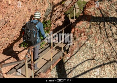 La femme Traverse le pont métallique suspendu sur le côté de la falaise Banque D'Images