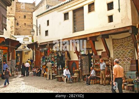 Les commerçants et leurs magasins vendant des assiettes en céramique et d'autres produits aux touristes de l'ancienne médina, Fes el Bali, à Fès Banque D'Images