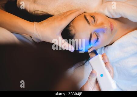 Un dermatologue attentif a une séance laser avec une dame brune caucasienne Banque D'Images