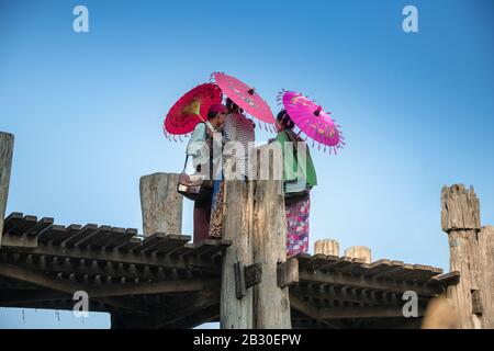 Mandalay, Myanmar - Janvier 2020: Les vendeurs locaux birmans qui détiennent des parapluies colorés vendent des souvenirs aux touristes au célèbre pont U Bein. Banque D'Images