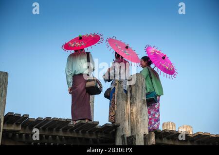 Mandalay, Myanmar - Janvier 2020: Les vendeurs locaux birmans qui détiennent des parapluies colorés vendent des souvenirs aux touristes au célèbre pont U Bein. Banque D'Images