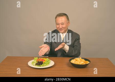 Portrait d'un homme d'affaires asiatique mûr avec de la nourriture au travail Banque D'Images