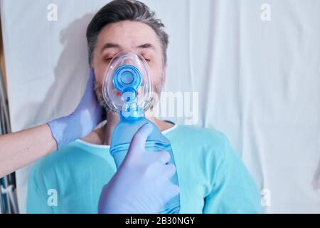 Au-dessus de la vue de l'infirmière dans les gants chirurgicaux dting sac masque de valve ventilation au patient sur la table chirurgicale Banque D'Images