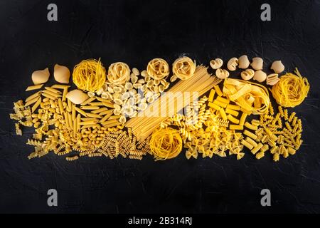 La texture des pâtes italiennes, une couche plate de divers types de pâtes, est tirée d'en haut sur fond noir Banque D'Images