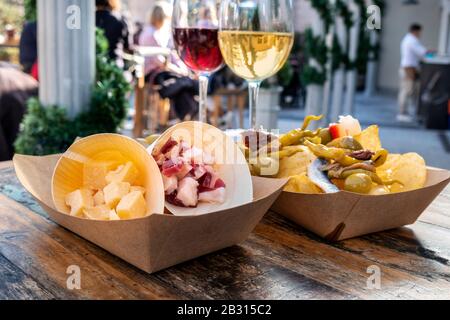 Bar à tapas. Fromage, jambon et pinchos avec verres de vin rouge et blanc sur une table en bois dans un café extérieur Banque D'Images