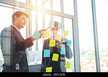 Collègue de deux personnes jeune homme d'affaires asiatique dans la communication formelle robe sur le mur dans le milieu de travail moderne. Banque D'Images