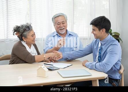 Souriant satisfait couple senior faisant la vente contrat de conclusion de contrat main obtenir la clé de maison de l'agent immobilier, famille et courtier heureux plus âgés Banque D'Images