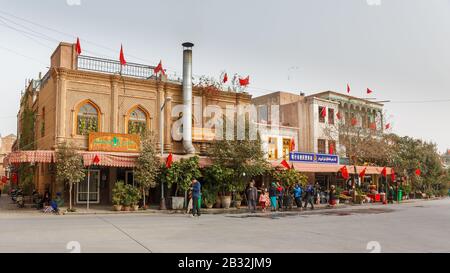 Rue dans la vieille ville de Kashgar : maisons de la minorité Uyghur avec un poste de police intégré. Drapeaux chinois dans tout le bâtiment. Banque D'Images