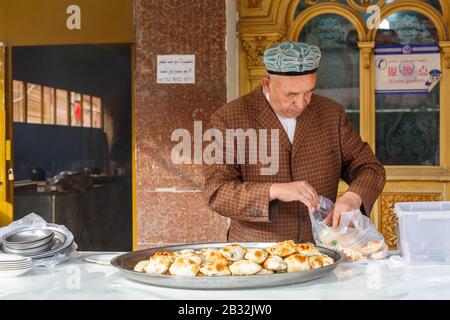 Uyghur homme mettant le samsa traditionnel dans un sac en plastique. Similaire À Indian Samosa. Boulangerie traditionnelle farcie de viande ou de légumes. Délicieux repas. Banque D'Images