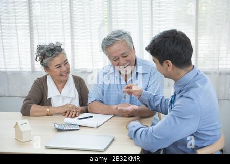 Souriant satisfait couple senior faisant la vente contrat de conclusion de contrat main obtenir la clé de maison de l'agent immobilier, famille et courtier heureux plus âgés Banque D'Images