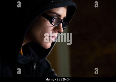 Femme caucasienne travaillant tard sur un ordinateur portable dans l'obscurité Banque D'Images