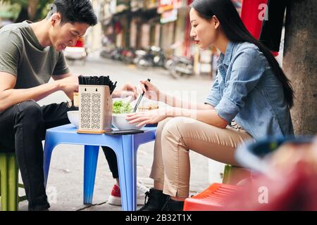 Les touristes mangeant de la nourriture de rue au Vietnam Banque D'Images