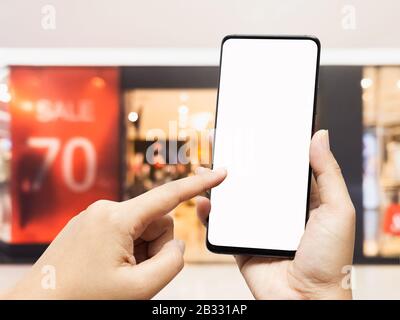 Téléphone portable avec poche à vêtements floutés et enseigne de remise. Mockup smartphone magasin de vêtements de détail remise vente 70% d'intérieur d'affichage Banque D'Images