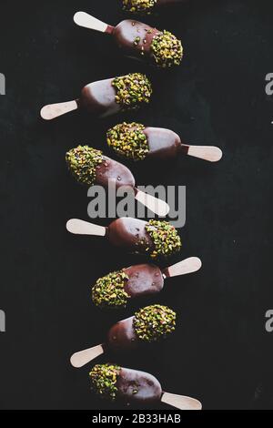 La glace à glaçage au chocolat surgit sur fond noir Banque D'Images