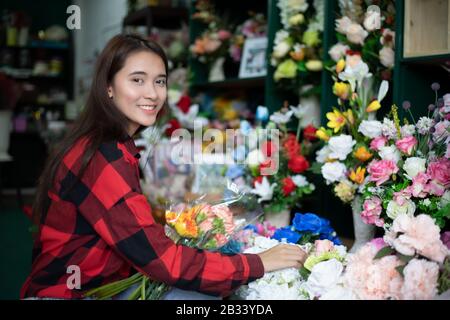 Femme souriante fleuriste petite entreprise propriétaire de fleuriste et jeune fleuriste examinant des fleurs à la boutique Banque D'Images