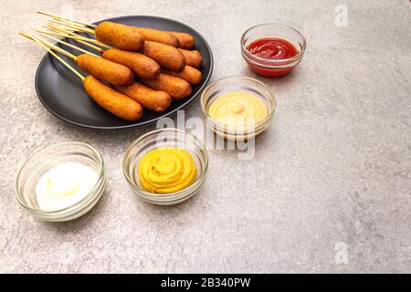 Des chiens de maïs faits maison avec des sauces populaires. Cuisine traditionnelle américaine de rue. Sur fond de pierre. Banque D'Images