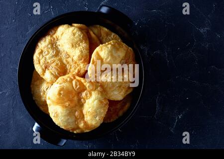 Bhatura, pain sauté frit profond indien dans un plat noir sur une table en béton, vue horizontale de dessus, plat, espace libre Banque D'Images