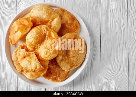 Gros plan de Bhatura, pain sauté frit indien sur un plateau blanc sur une table en bois, vue horizontale de dessus, plat, espace libre Banque D'Images