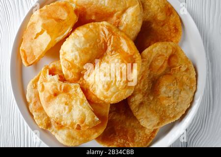 Gros plan de Bhatura, pain sauté frit indien sur un plateau blanc sur une table en bois, vue horizontale de dessus, plat, espace libre Banque D'Images