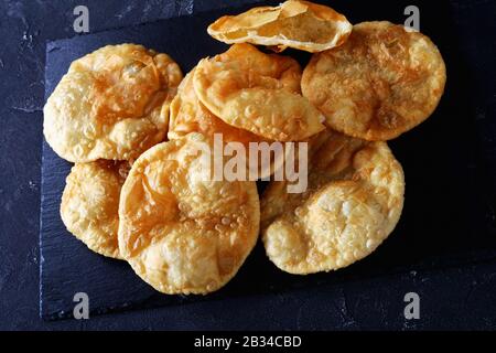 Gros plan de Bhatura, pain indien sauté frit sur un plateau noir en ardoise sur une table en béton, vue horizontale d'en haut Banque D'Images