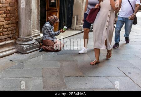 Les femmes mendient dans les rues de Venise, en Italie, tandis que les touristes passent en ignorant Banque D'Images