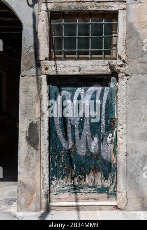 Graffitis sur une vieille porte verte peinte peeling à Venise, Italie Banque D'Images