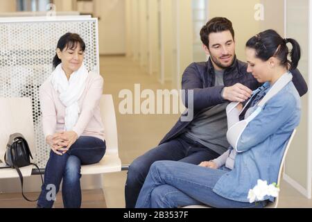 couple dans la salle d'attente médicale femme a bras dans le harnais Banque D'Images