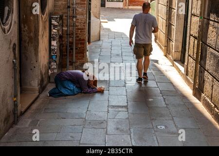 Les touristes marchant par des femmes mendiant dans les rues de Venise, Italie Banque D'Images