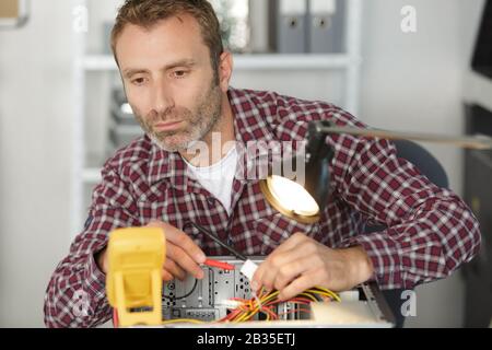 électricien à l'aide d'un multimètre pour tester l'ordinateur Banque D'Images