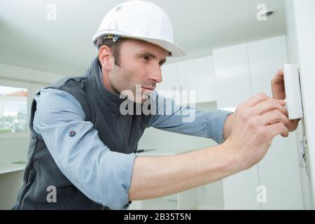 portrait de l'homme pendant l'installation de la base du thermostat Banque D'Images