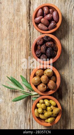 Variété d'olives dans des bols en bois, table en bois, vue sur le dessus. Apéritif méditerranéen sain et délicieux Banque D'Images