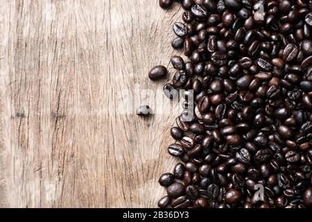 Grains de café rôtis sur fond en bois, boisson de café artisanale Banque D'Images