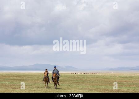 Mongolie, municipalité d'Ulan-Bator, près de Nalayh, deux garçons à cheval dans la steppe herbacée Banque D'Images