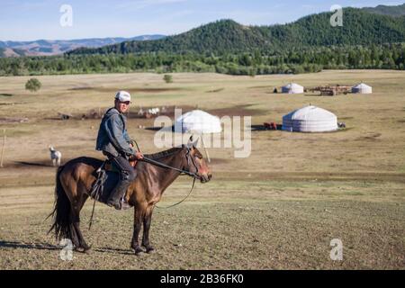 Mongolie, province de Tov, Parc national de Gorkhi-Terelj, jeune homme qui monte un cheval devant un camp de yourte Banque D'Images