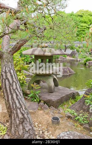 Lanterne traditionnelle en pierre (toro) sur l'étang du jardin Kokoen près du château Himeji, Japon. Le jardin a été aménagé en 1992 Banque D'Images