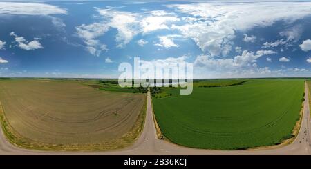 Paysage de champ vert et marron. Terres agricoles et route. Magnifique ciel bleu avec de grands nuages Banque D'Images