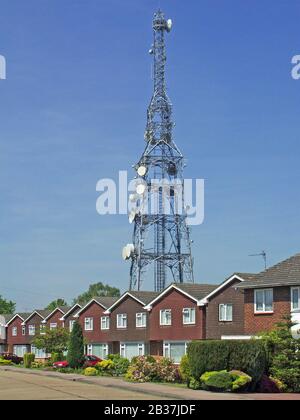 Route avec rangée de même style maison indépendante et jardin avant sous la grande cellule de communication mât télécommunications satellite parabole Brentwood UK Banque D'Images