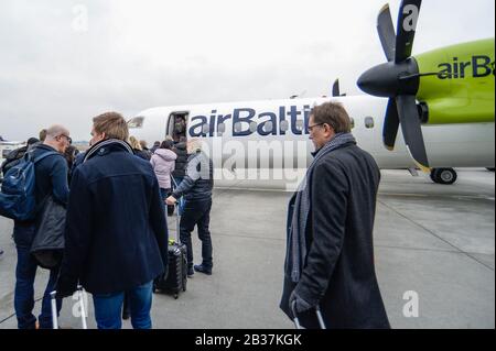 Les passagers embarquant un avion balte Bombardier Q400 de la prochaine génération à l'aéroport Chopin de Varsovie. Banque D'Images