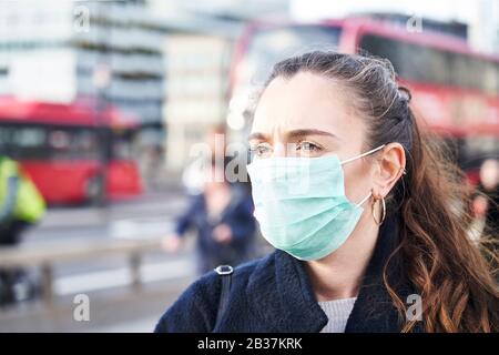 Jeune femme portant un masque de visage tout en marchant dans les rues de Londres Banque D'Images